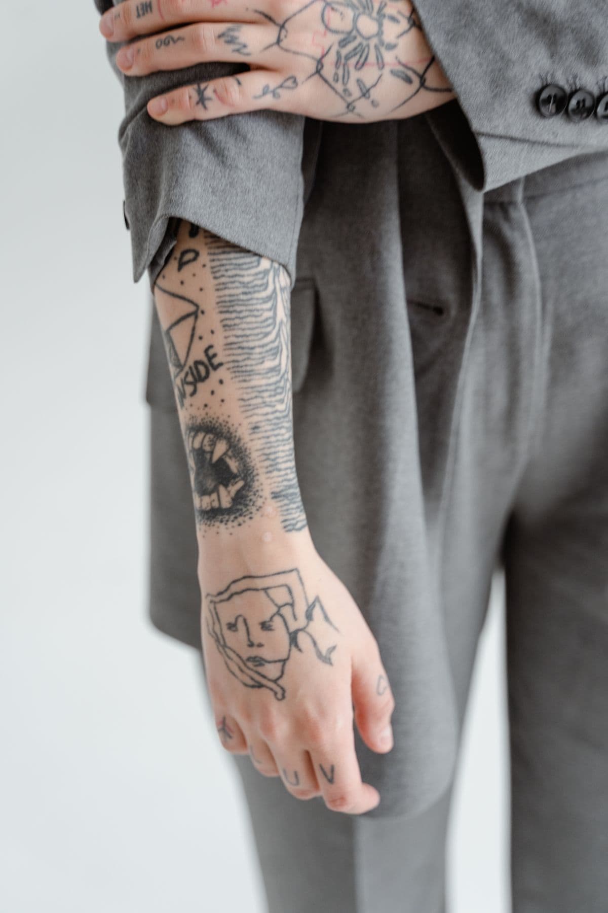 Tattooed forearm under a rolled-up suit sleeve