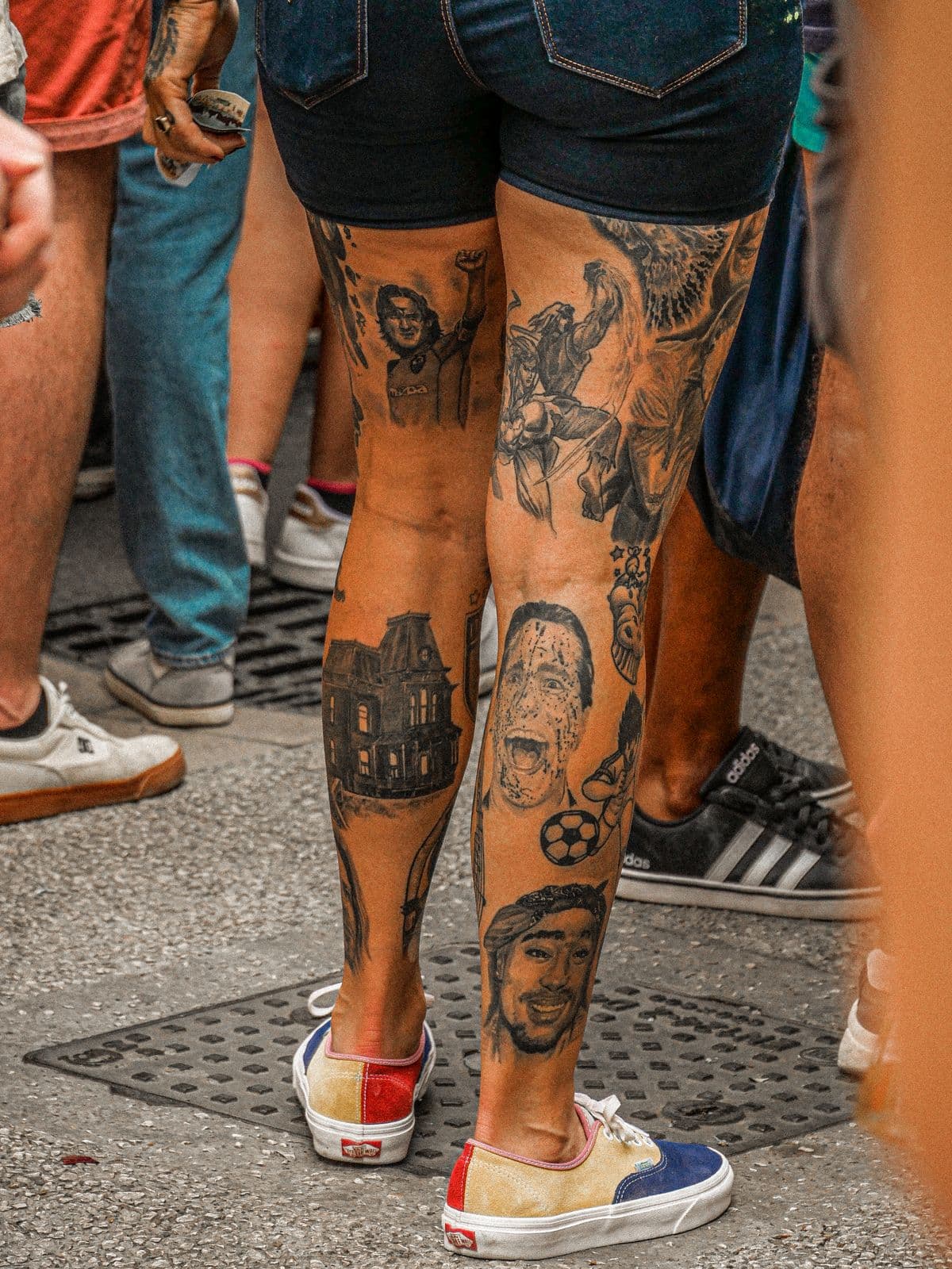 Tattooed legs standing on a sidewalk